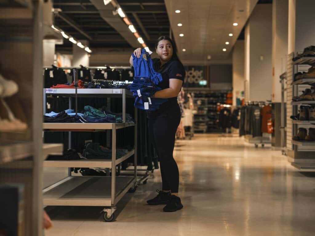 Retail worker sorts out clothes on the shelves at Kmart.