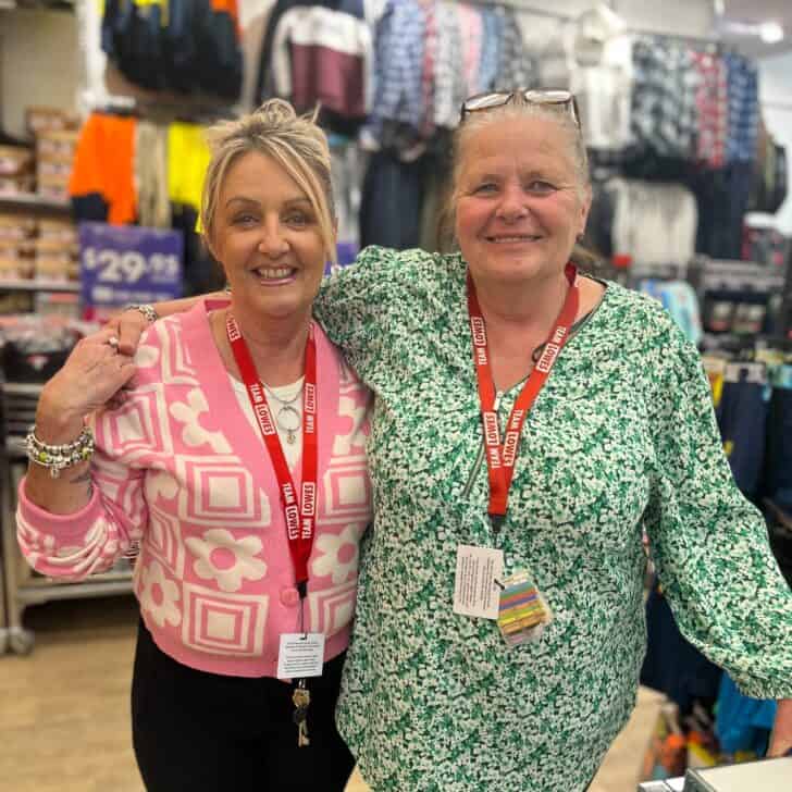 Two SDA members working at Lowes. They are both smiling and have their arms around each other.